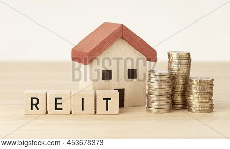 Reit Real Estate Investment Trust Concept. House Model, Money And Wooden Blocks With Text