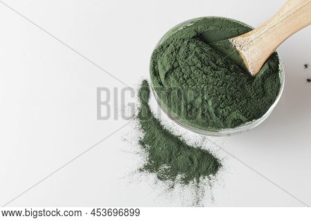 Natural Additives And Superfood. Green Spirulina Algae Powder In Glass With Wood Spoon On White Back