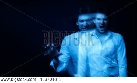 Man With Mental Disorders And Schizophrenic Disease In White Shirt On Dark Background
