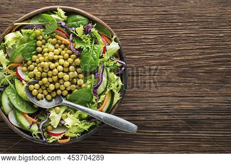 Green Lettuce Salad Meal With Fresh Vegetables And Cooked Peas On Wooden Table Background