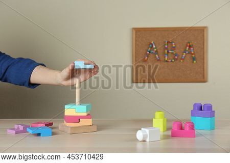 Child Playing With Toy Pyramid At Wooden Table Indoors, Closeup. Aba Therapy Concept