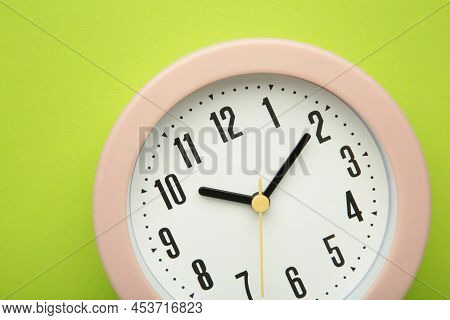 Pink Clock On Green Background. Top View. Macro