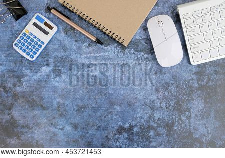 Blank Notebook Is In The Middle Of Office Desktable With Pen And Office Supplies. Top View, Flat Lay