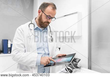 Doctor Examine An X-ray Image Of A Patient In Digital Tablet At Doctor Office. High Quality Photogra