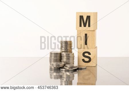 The Word Mis Is Laid Out Of Wooden Cubes With Letters On White Background With Coins. Mis - Short Fo