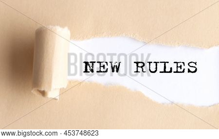 The Text New Rules Appears On A Torn Paper On White Background.