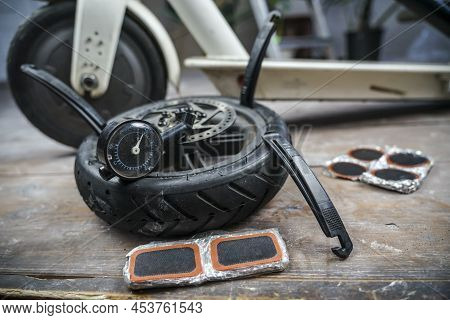 The Wheel From The Electric Scooter Lies Next To The Scooter With A Plastic Paddle For Wheel Boring.