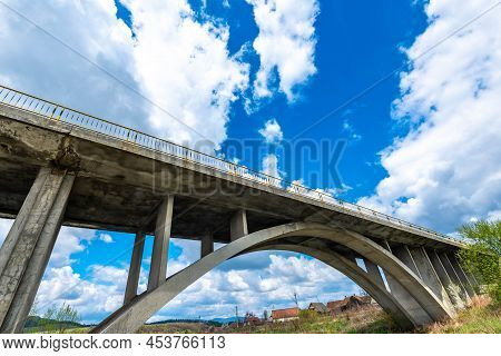 Concrete Bridge In Arch Shape Over Olt River In Transylvania, Romania, Blue Sky With White Clouds Ba