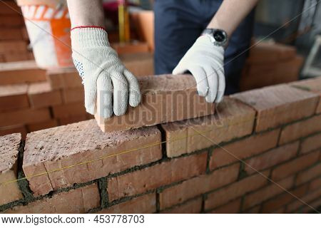 Close-up Of Male Builder Hands Making Make Brickwork Using Red Bricks. Builder Building Brick Wall I