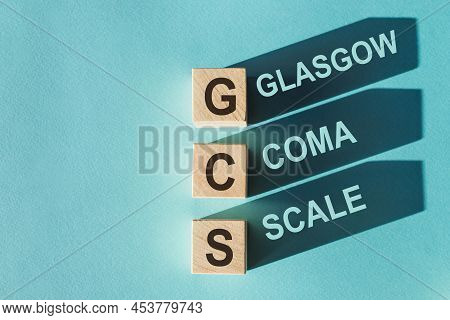 Gcs Glasgow Coma Scale Text, Written On Wooden Blocks With Shadows On Blue Background.