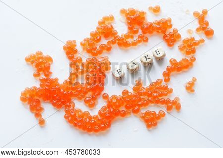 Artificial Fake Red Caviar On A White Background Next To The Fake Inscription. Сoncept Of Non-natura
