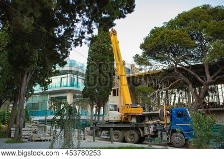 A Truck With A Telescopic Crane Delivers Packages Containing In City Near The Trees