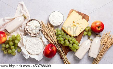 Shavuot Flat Lay With Dairy Products, First Fruits And Wheat On Light Gray Background. Jewish Shavuo