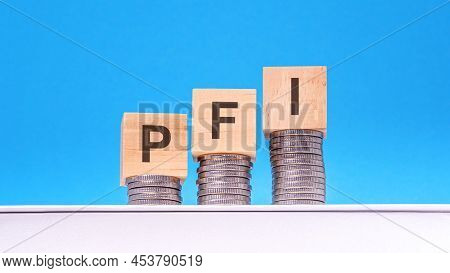 Pfi - Private Finance Initiative - Text On Wood Cube Block Stack With Coins, Blue Background, Busine