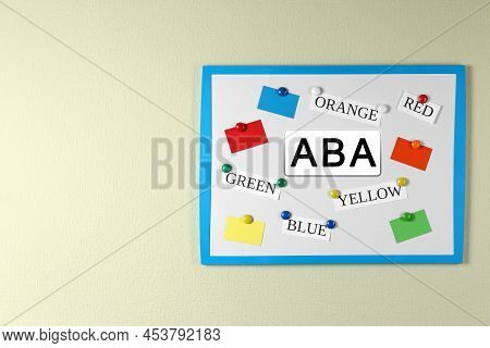 Board With Abbreviation Aba And Different Colors On Beige Wall, Space For Text