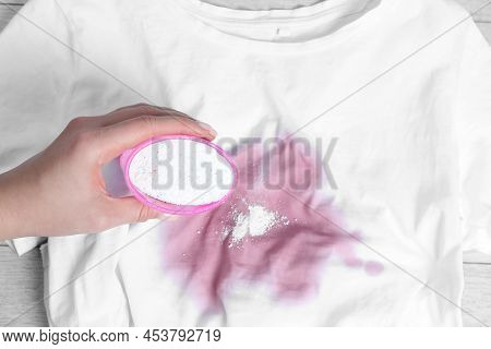 Woman Adding Powdered Detergent Onto White T-shirt With Stain On Wooden Surface, Top View. Hand Wash