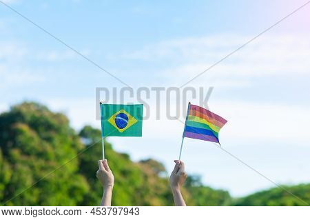 Hands Showing Lgbtq Rainbow And Brazil Flag On Nature Background. Support Lesbian, Gay, Bisexual, Tr