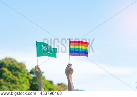 Hands Showing Lgbtq Rainbow And Saudi Arabia Flag On Nature Background. Support Lesbian, Gay, Bisexu