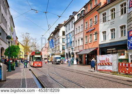 Freiburg, Germany - April 2022: City Center With Shops And People Walking By On Sunny Spring Day