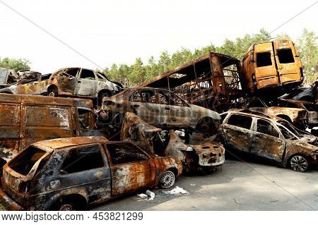 Ukrainian Man Stands Against The Background Of Broken And Burnt Cars Affected By Russian Missiles. D