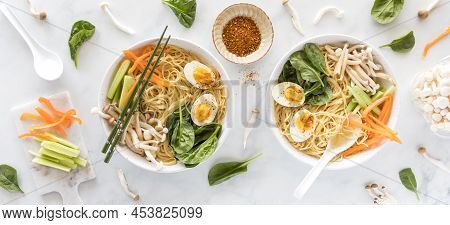Top Down View Of Bowls Of Vietnamese Pho Soup Surrounded By Ingredients.