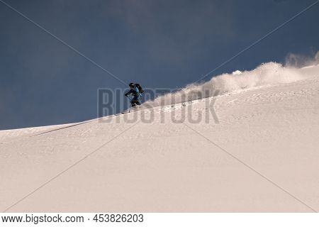 Great View On Active Snowboarder Riding Down From Snowy Mountain On Splitboard And Splashes Snow.