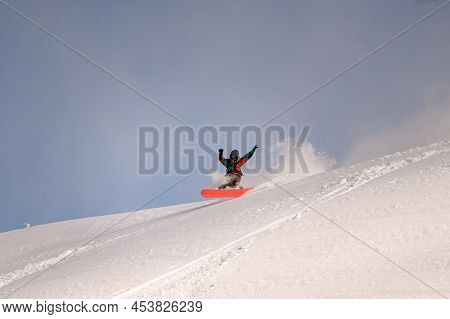 Active Snowboarder In Bright Overalls Slides Down The Mountain On Splitboard On Powdery Snow