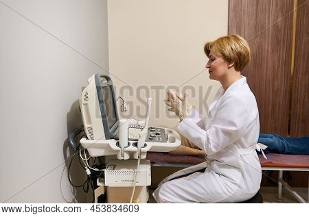Pleasant Female Radiologist Doctor Holds An Ultrasound Probe In One Hand And Looks At The Monitor Sc