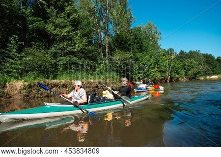 Family Kayak Trip. Man And Woman And Elderly Couple Senior And Seniora Rowing Boat On The River, A W