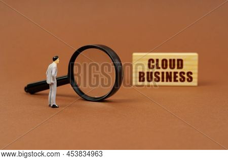 Business Concept. A Figurine Of A Businesswoman Looks Through A Magnifying Glass At A Block With The