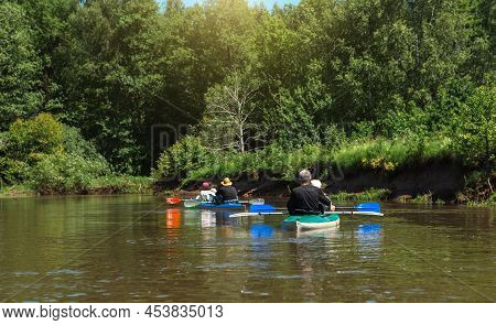 Family Kayak Trip. Man And Woman And Elderly Couple Senior And Seniora Rowing Boat On The River, A W
