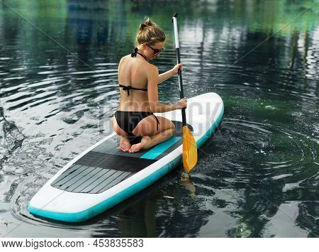 Young Woman On Paddle Board On A River. Relaxing On Vacation