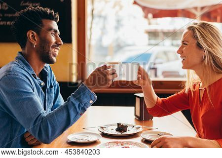 Interracial Couple Toasting With A Cup Of Coffee
