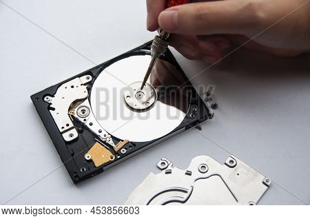 The Abstract Image Of Inside Of Hard Disk Drive With Technician Fixing Using Screw Driver On White B