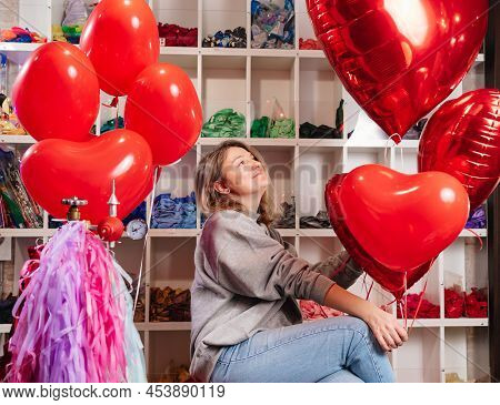 Woman On Red Decorative Barrel. With A Large Red Balloons In The Shape Of Heart.