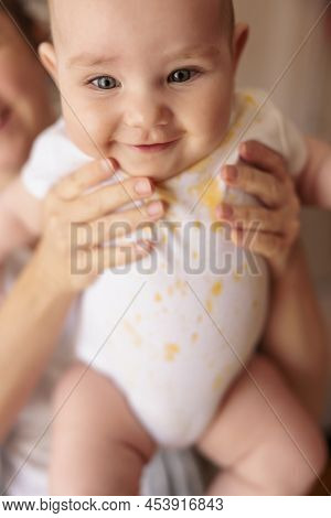 Mother Holding Her Happy Cheerful Baby Boy After Introducing First Solid Food Meal, All Messy And St