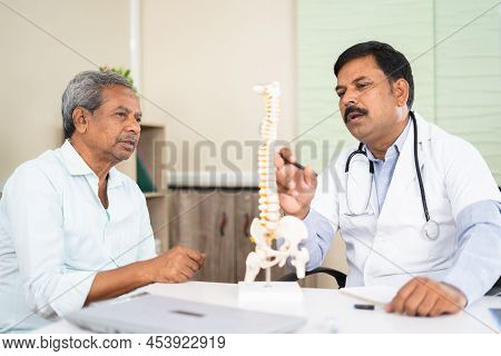 Doctor Explaining To Senior Patient Abour Back Pain Using Spinal Model At Hospital - Concept Of Cons