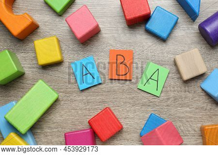 Colorful Building Blocks And Cards With Abbreviation Aba On Wooden Table, Flat Lay
