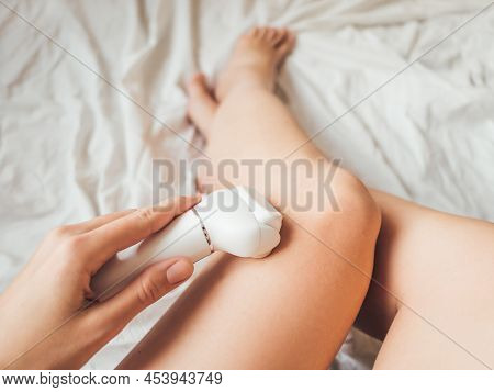 Woman Takes Care Of Herself, Depilated Legs With Epilator. Epilation Cosmetological Procedure For Ha