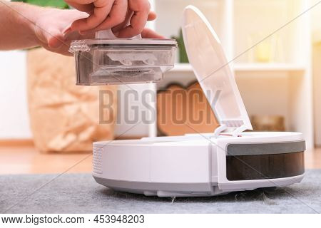 A Man Takes Out A Garbage Container From A Robot Vacuum Cleaner. The Container Is Full Of Wool, Dust