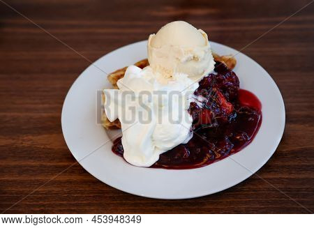 A Plate With Waffle, Vanilla Sauce, Cream And Cherries.