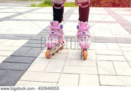 The Girl Rides On Pink Roller Skates With A View Of Her Legs. Part Of The Body In The Form Of Legs W