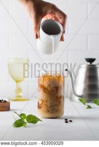 Cream Is Poured Into Cold Black Coffee With Ice Cubes. Coldbrew. Summer Drinks.
