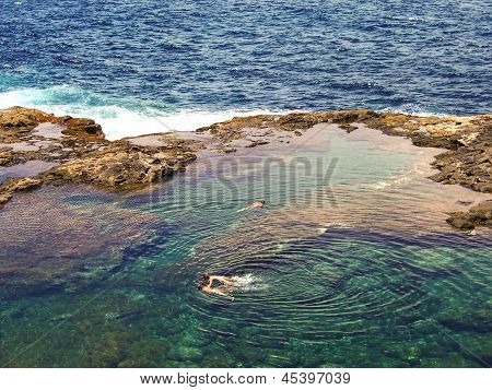 Gente de buceo en una cuenca Natural en la costa de rocas de Lanzarote