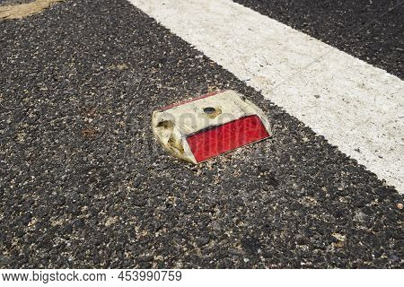 Metal Road Stud With Red Reflector On Asphalt Road With White Painted Lane Marking Line As Divider O
