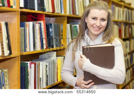 student standing at bookshelf in old library