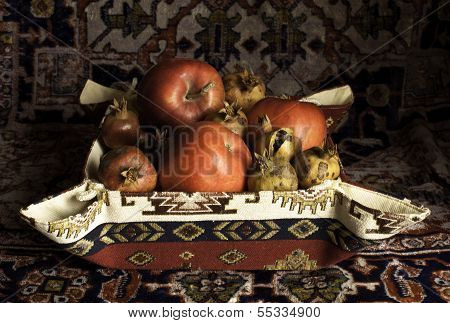 Still life of Armenian pomegranate, apples and carpet