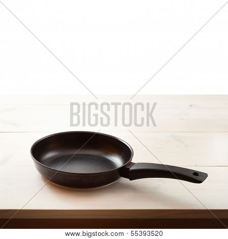 Empty frying pan on wooden background.