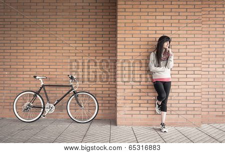 Sportive woman with fixie bike over a brick wall