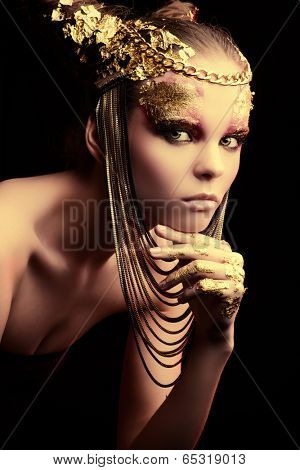 Art project: beautiful woman with golden make-up. Jewelry, make-up. Fashion. Over black background.